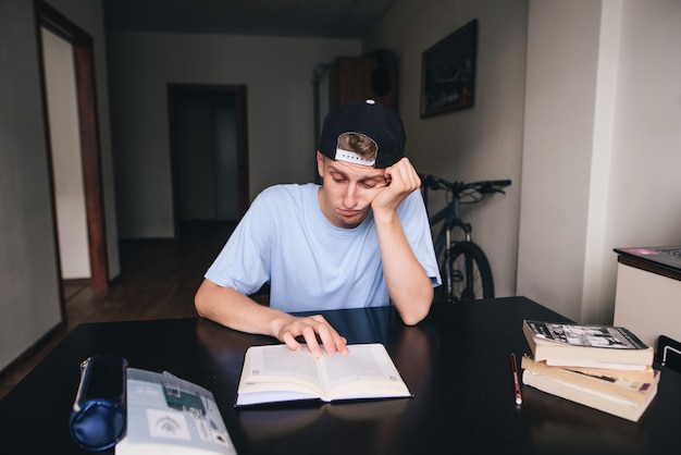 Een trieste student is terughoudend om een boek in zijn kamer te lezen. Huiswerk aan het maken. Thuis lesgeven