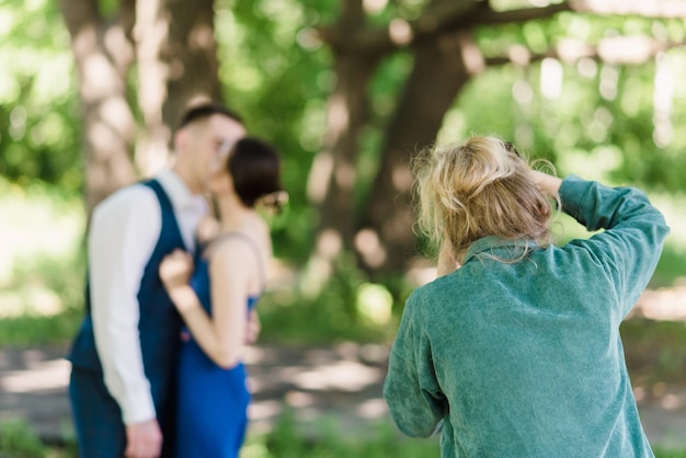 Een trouwfotograaf fotografeert een stel in de natuur op een zonnige dag