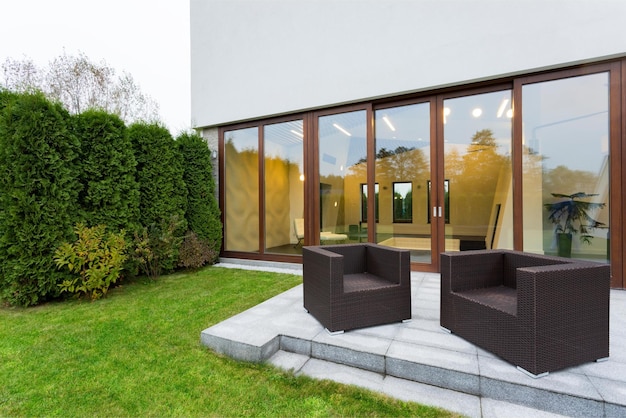 Foto een tuin buiten het huis met een terras en stoelen