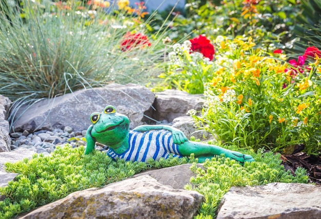 Een tuinbeeld van een kikker die op de grond ligt en een boek leest