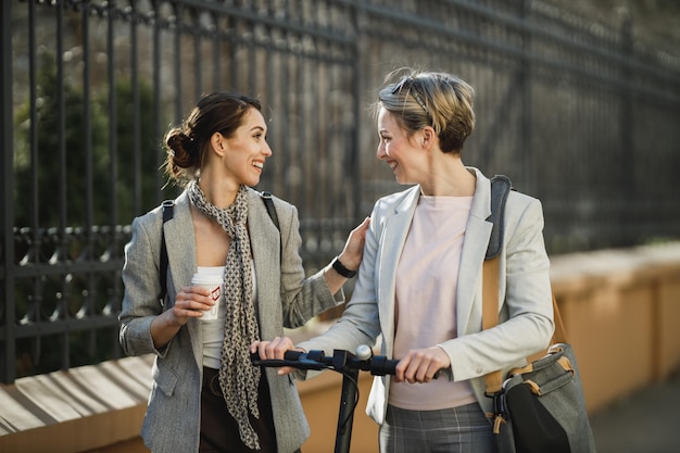 Een twee succesvolle zakenvrouwen die een snelle koffiepauze hebben en kletsen terwijl ze door de stad wandelen.