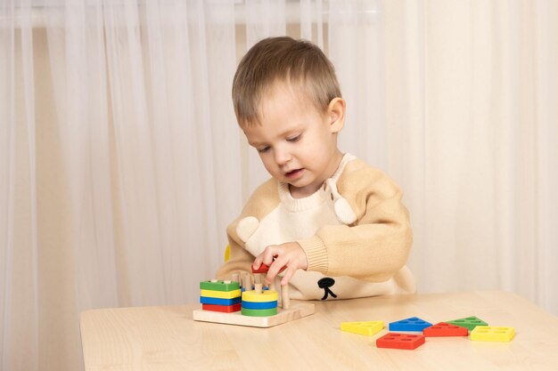 Foto een tweejarig jongen speelt met houten speelgoed om zijn logische en motorische vaardigheden te ontwikkelen