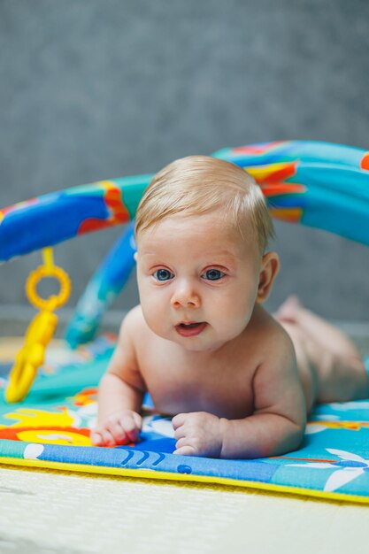 Een tweemaandige baby ligt op een ontwikkelingsmat en speelt met speelgoed Tijdens het spelen leert het kind de wereld kennen en leert vormen en kleuren.