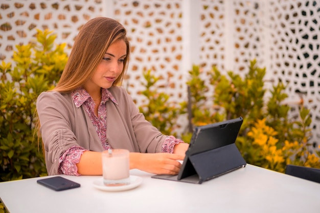 Een uitvoerende vrouw en zakenvrouw die ontbijten in een restaurant en de agenda bekijken op een tablet