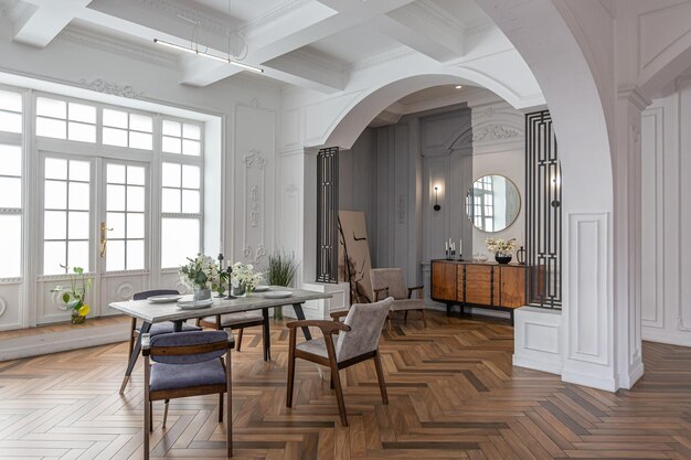 een uitzicht op een set eettafel in een chique dure heldere interieur van een enorme woonkamer in een historisch herenhuis met gebogen bogen kolommen en witte muren versierd met ornamenten en stucwerk