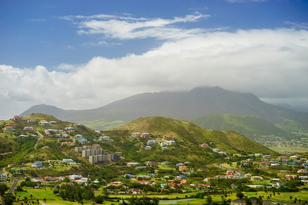 Een uitzicht over St. Kitts Island met woonwijk en weelderige groene heuvels op de achtergrond.