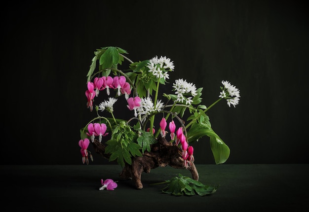 Een vaas met bloemen en bladeren met daarop roze bloemen Allium ursinum Dicentra