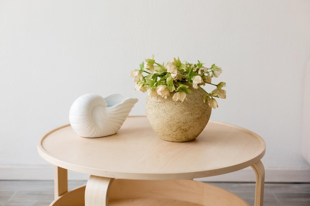 Een vaas met bloemen en een keramische vaas op een houten tafel tegen een witte muur in de kamer