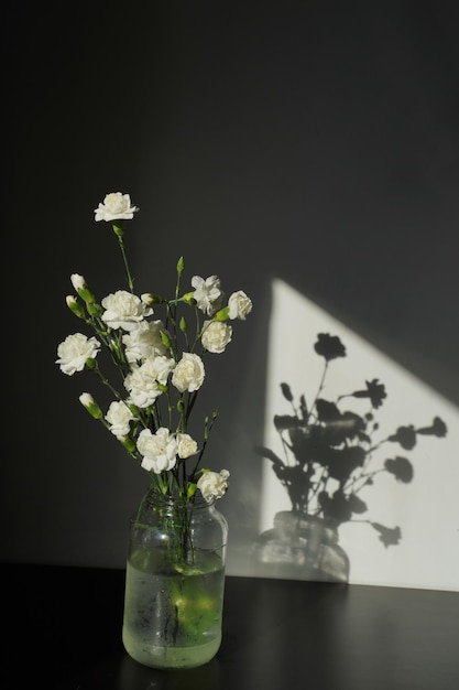 Foto een vaas met bloemen waar de zon op schijnt