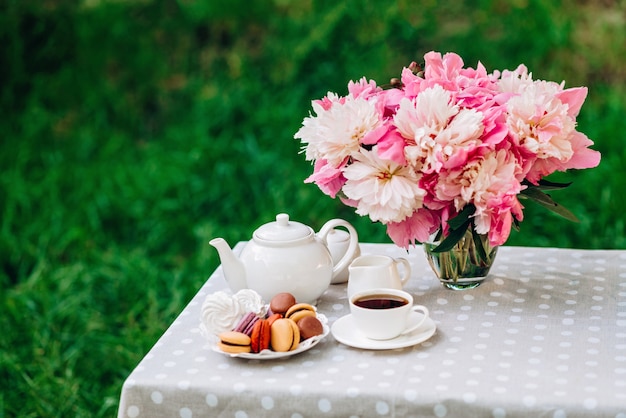 Een vaas met pioenrozen een theepot en een kopje thee op tafel