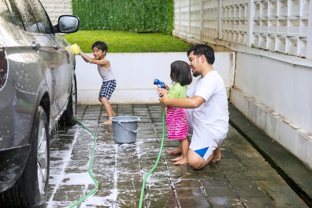 Een vader die zijn kinderen leert een auto te wassen