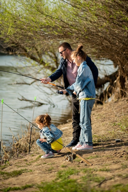 Een vader en zijn twee dochters vissen in de rivier.