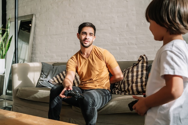 Een vader en zijn zoon hebben plezier terwijl ze thuis samen videogames spelen. Monoparental familieconcept.