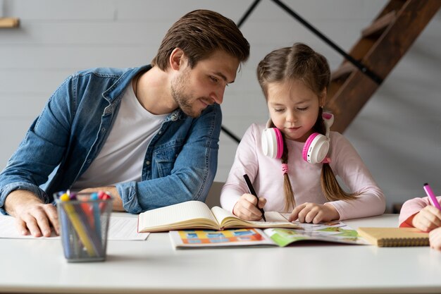 Een vader helpt zijn dochtertje om haar huiswerk voor de school te maken.