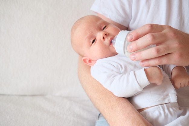 Een vader houdt zijn pasgeboren baby vast en voedt hem met de fles.