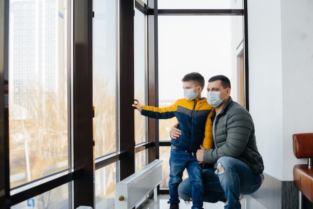 Een vader met zijn kind staat tijdens de quarantaine in een masker. Pandemie, coronavirus