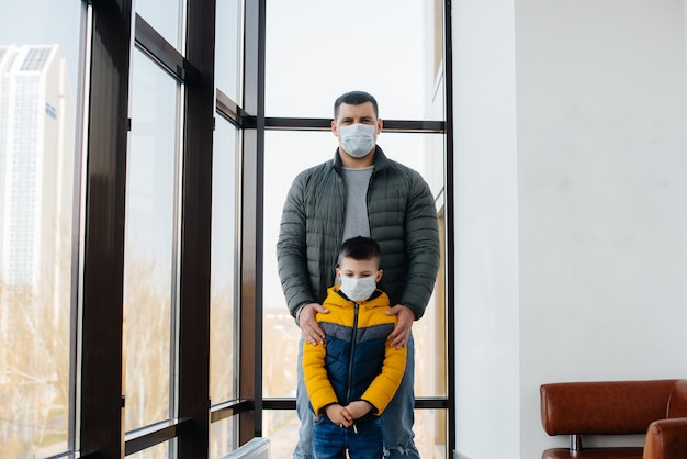 Een vader met zijn kind staat tijdens de quarantaine in een masker. Pandemie, coronavirus.