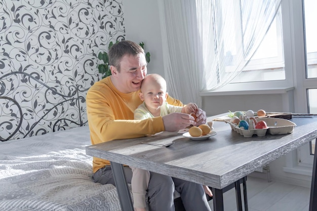 Een vader viert Pasen met zijn jonge zoon Ze slaan eieren, eten eieren en ontbijten Vader leert het kind