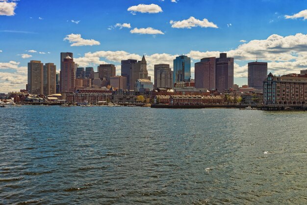 Een van de kant van de rivier Charles en de skyline van Boston in de Verenigde Staten. De stad is de thuisbasis van 251 voltooide wolkenkrabbers. Het ligt in de buurt van water en boten zijn een veelvoorkomend vervoermiddel.