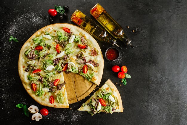 Een vegeterian pizza withvagetables en kruiden op zwarte achtergrond