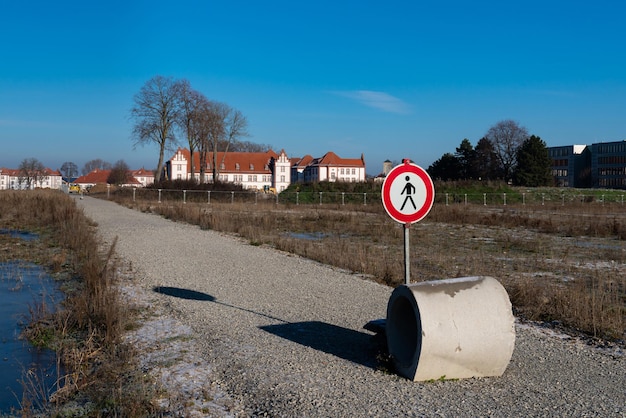 Een verbodsbord voor voetgangers en een betonnen ring op een eenzaam pad dat naar een bouwplaats leidt