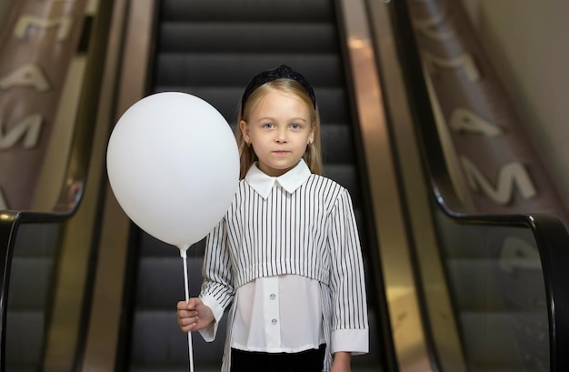 Een verdrietig klein meisje met een witte luchtgarik staat bij de extreme metro