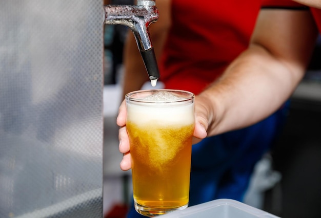 Een verfrissend bier uit de kraan in een glas bij een bar gieten