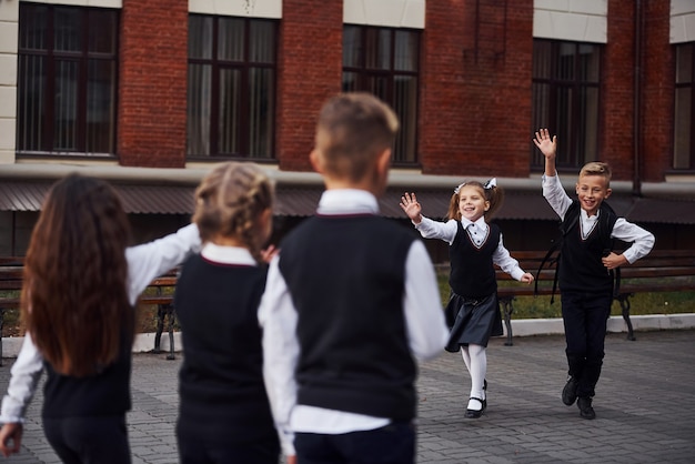 Een vergadering hebben. Groep kinderen in schooluniform dat buiten samen is in de buurt van het onderwijsgebouw.