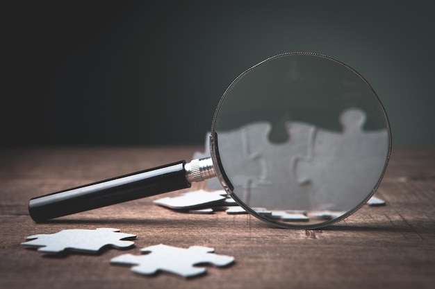 Een vergrootglas en puzzelstukjes op tafel