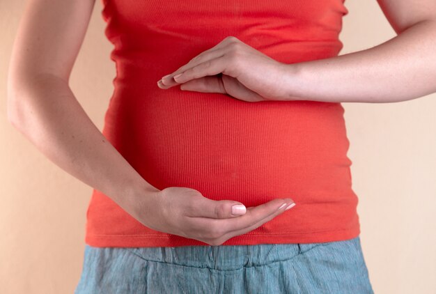 Een vergrote weergave van de buik van een zwangere vrouw in een rood T-shirt