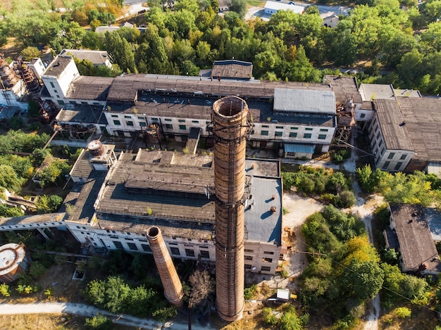 Een verlaten fabriek omgeven door weelderig groen, twee grote buizen