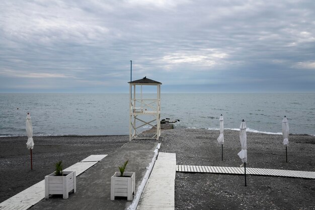 Een verlaten strand aan de kust van Sotsji en een reddingstoren tegen de achtergrond van een bewolkte lucht en een stormachtige Zwarte Zee Adler Krasnodar Territory Rusland