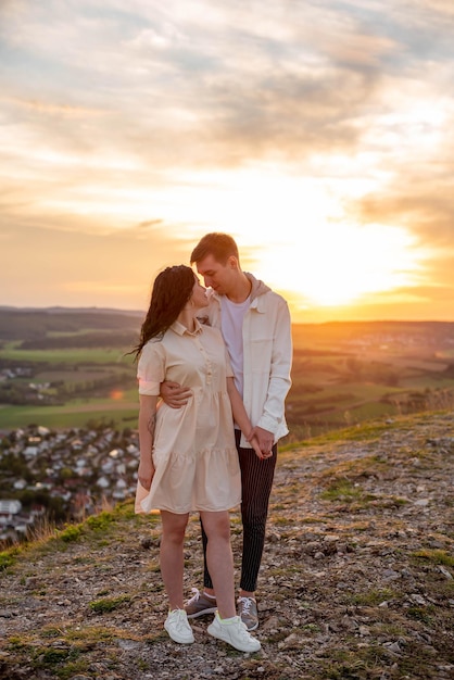 Een verliefd stel, een jongen en een meisje staan bij zonsondergang op een berg te knuffelen en te zoenen