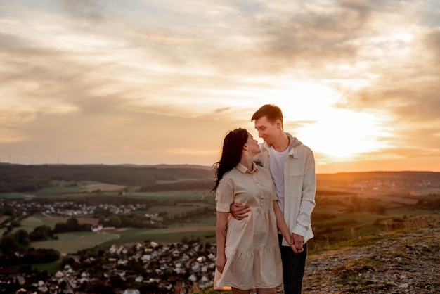 Een verliefd stel, een jongen en een meisje staan bij zonsondergang op een berg te knuffelen en te zoenen