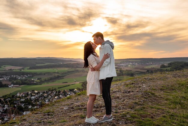 Een verliefd stel staat op een berg bij zonsondergang