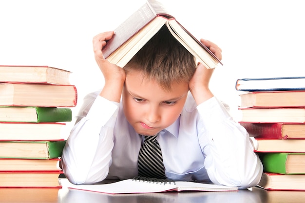 Een vermoeide, achterblijvende schooljongen zit in een bibliotheek met boeken en leert lessen. Onwil om te leren.