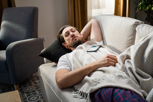 Een vermoeide man slaapt in de woonkamer na een vermoeiende week op het werk, rustend en herstellende brunette