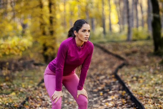 Een vermoeide sportvrouw neemt een pauze van fitness in de natuur