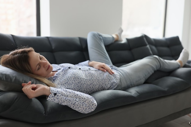 Een vermoeide vrouw ontspant op een comfortabele bank na hard werken in een tevreden vrouwelijke persoon op kantoor