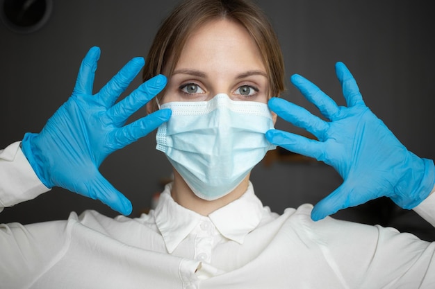 Een verpleegster met een beschermend masker en handschoenen laat al haar vingers zien