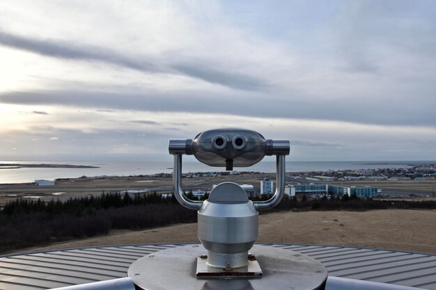 Foto een verrekijker met een munt op zee tegen een bewolkte hemel.