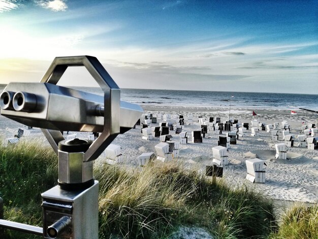 Foto een verrekijker met muntstukken bij kapstoelen op het strand