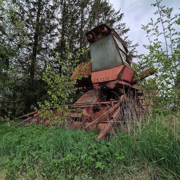 Een verroeste oude tractor zit in een grasveld.