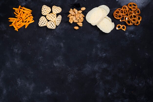 Een verscheidenheid aan snacks en snacks voor bier op een betonnen zwarte tafel