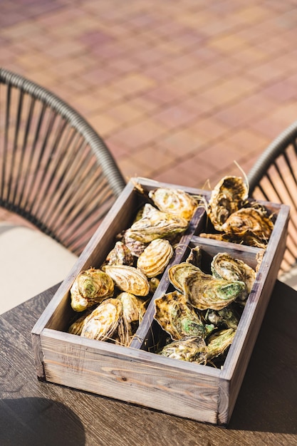 Een verscheidenheid aan verse oesters met limoen en citroen in houten kist Verse zeevruchten Terras buitencafé