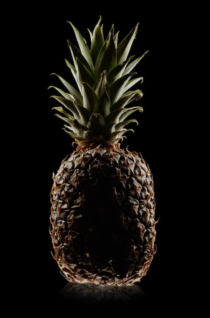 Foto een verse ananas op zwarte achtergrond. rustige techniek