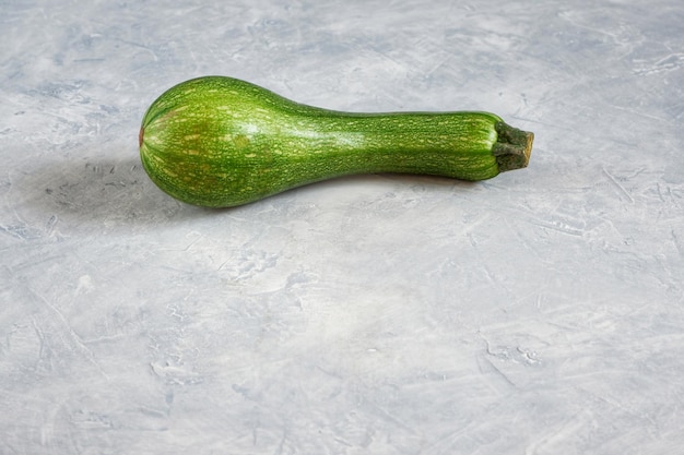 Een verwende courgette op een grijze achtergrond Lelijke voedselconcept biologische groenten Met selectieve focus