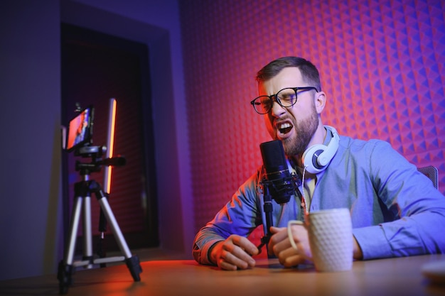 Een videoblogger neemt content op in zijn studio De host van de videoblog is een jonge man die heel enthousiast zijn abonnees een verhaal wil vertellen