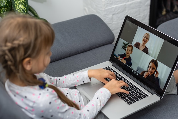 Een videoconferentie van een meisje met een gelukkige vrouwelijke leraar op laptop