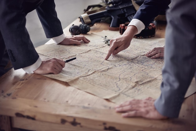 Een vijandige overname plannen Twee mannen in pakken bespreken plannen terwijl geweren en een kaart op tafel liggen